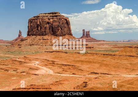 Foto aerea di strada sterrata con piccole auto in un bellissimo paesaggio desertico con enormi Mesa rossi sullo sfondo Foto Stock
