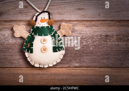 Decorazione di Natale fatta a mano feltro pupazzo di neve. Stile vintage, su sfondo di legno antico, con spazio per il tuo testo. Foto Stock