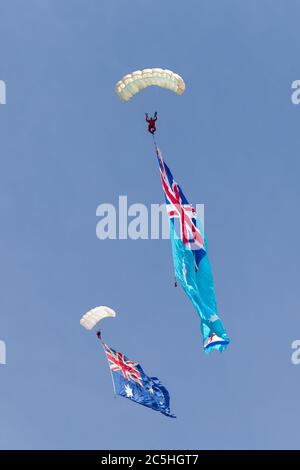 Due paracadutisti che scendono con una bandiera australiana e la bandiera dell'aviazione reale australiana. Foto Stock