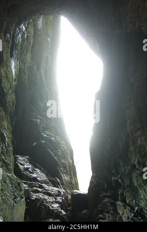 Luce che splende attraverso la fessura in una grotta, Thor's grotta nel quartiere di picco Foto Stock