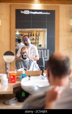 Mehmet Yusuf, proprietario di Chaplin's of London Barbers a Brockley, a sud di Londra, dimostra i dispositivi di protezione individuale (PPE) che saranno utilizzati al momento della riapertura al pubblico quando l'abolizione di ulteriori restrizioni di blocco in Inghilterra entrerà in vigore il sabato. Foto Stock