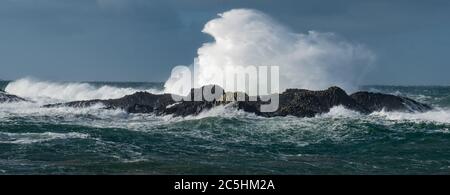 Onde massicce si schiantano sulle rocce a Ballintoy Harbour, Causeway Coast, Irlanda del Nord Foto Stock