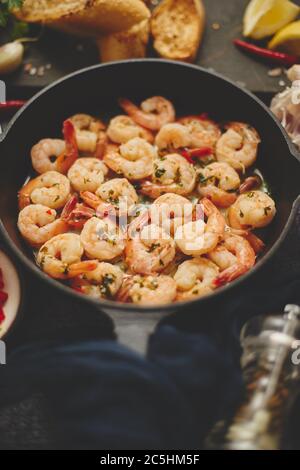 Gustose code di gamberi fritte nel burro con aglio, prezzemolo, peperoncino di vino bianco. Con vari ingredienti Foto Stock