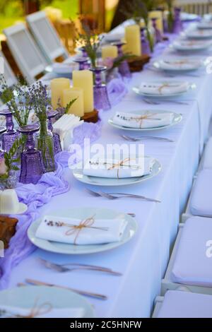 Elegante tavolo per matrimonio fidanzato cena di Pasqua con piatti bianchi in ceramica tovagliolo di cotone legato con spago lavanda fiori candele. Provenza Foto Stock