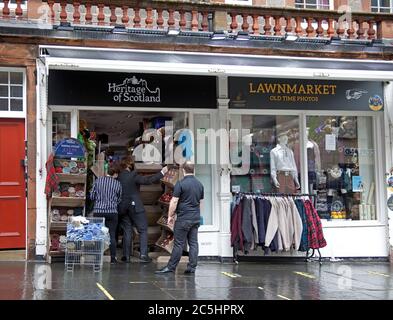 Lawnmarket, Royal Mile, Edimburgo, Scozia, Regno Unito. 3 luglio 2020. Nel giorno in cui la restrizione di viaggio di cinque miglia viene revocata in Scozia, mentre le restrizioni del virus Covid-19 si attenuano, alcuni negozi turistici ottimisti stanno aprendo le porte al pubblico. Personale con foto che organizza mostre di merci Foto Stock