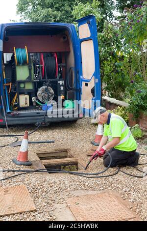 BUCKINGHAM, Regno Unito - 07 agosto 2015. Azienda di pulizia di scarico, uomo che eietta scarico di scarico di scarico fuori casa, Regno Unito Foto Stock