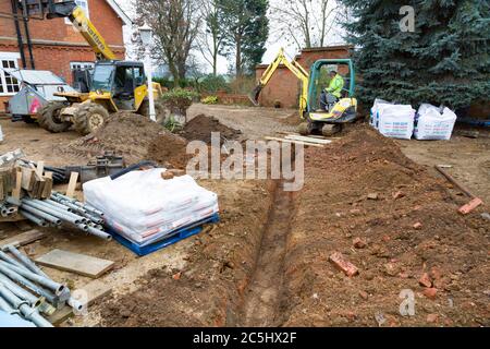 BUCKINGHAM, Regno Unito - 02 dicembre 2016. Driver Digger, scavando una trincea per gli scarichi in un cantiere edile del Regno Unito Foto Stock