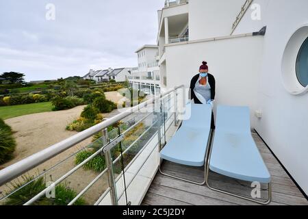 La governante Carolanne Rowe indossa dpi mentre sposta lettini su un balcone in una suite d'albergo presso il St Moritz Hotel and Spa, Cornovaglia, durante la preparazione della camera, prima della riapertura agli ospiti quando l'eliminazione di ulteriori restrizioni di blocco in Inghilterra entra in vigore il sabato. Foto Stock