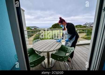 La governante Carolanne Rowe indossa i dpi mentre pulisce un balcone da pranzo in una suite d'albergo al St Moritz Hotel and Spa, Cornovaglia, durante la saintising in camera in preparazione prima della riapertura agli ospiti quando l'eliminazione di ulteriori restrizioni di blocco in Inghilterra entra in vigore il sabato. Foto Stock