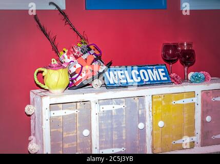 Festa colorata con decorazioni fantasia di cappelli, teapot, farfalla e cartello con gesso Foto Stock