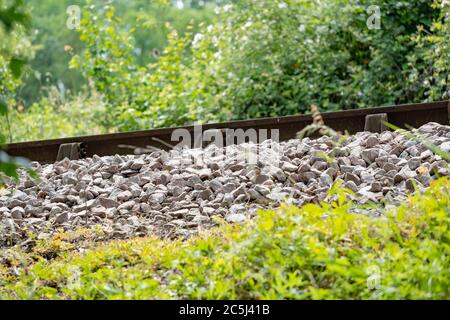 Vista insolita di un lato di una pista ferroviaria e di una zavorra appena installati, mostrata in salita su una pendenza netta. Foto Stock