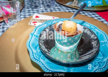 Una colorata festa del tè con cupcake al cioccolato e biscotti con cucchiaino da tè pronti per essere consumati su un piatto blu Foto Stock