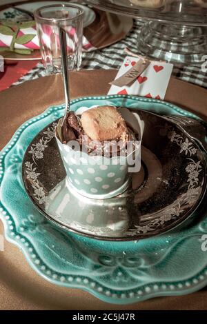 Una colorata festa del tè con cupcake al cioccolato e biscotti con cucchiaino da tè pronti per essere consumati su un piatto blu Foto Stock