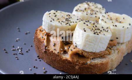 fast food, snack, burro di arachidi e sandwich di banana con semi di cia su un piatto Foto Stock