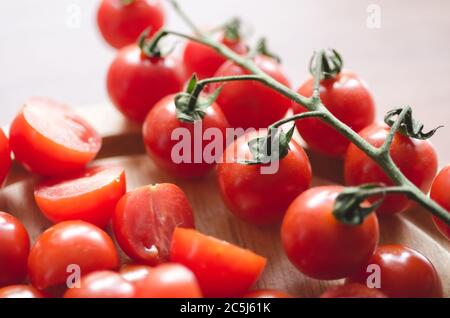 Primo piano di pomodori ciliegini rossi su scrivania in legno in cucina, interni, luce naturale Foto Stock