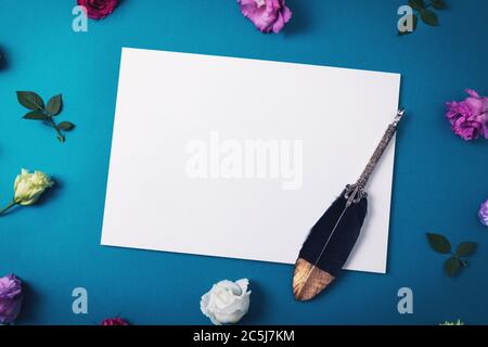 carta bianca con penna di quill vintage e fiori su sfondo blu Foto Stock