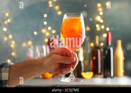 La mano maschio tiene il vetro di aperol Spritz. Cocktail estivo Foto Stock