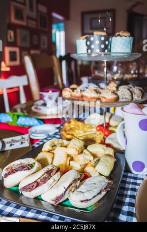 Una colorata festa del tè con cupcake al cioccolato, biscotti, muffin, palle dolci, panini con salsiccia, quiche di zucca si prepara su un'elegante bancarella per torte Foto Stock