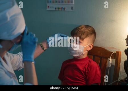 Bambino su appuntamento con un optometristo. La dottoressa controlla la vista del ragazzo. Ospedale cittadino. Maggio, 2020, Brovary, Ucraina Foto Stock