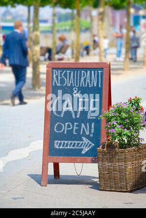 Ristorante che annuncia la riapertura dopo il blocco corona sul cartellone, gastronomia business open segno all'aperto. Foto Stock