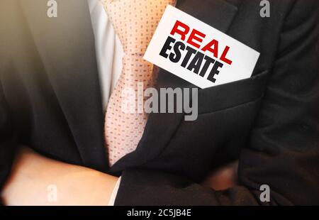 Parole immobiliari sulla carta un uomo d'affari tiene nella tasca superiore del suo vestito. Concetto di business immobiliare Foto Stock