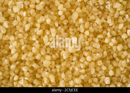 Un macro closeup di couscous crudo - minuscoli granuli di pasta fatti di grano duro / semola al vapore e essiccati utilizzati per cucinare un piatto nordafricano Foto Stock