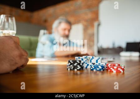 Focus su dibs. Primo piano gruppo di amici felici e maturi che giocano carte e bevono vino. Guarda felice, eccitato. Uomini caucasici che giocano a casa. Emozioni sincere, benessere, concetto di espressione facciale. Foto Stock