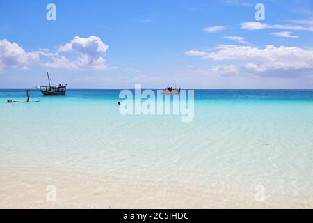 Kendwa, Zanzibar - 3 ottobre 2019: Oceano Indiano, spiaggia, barche e turisti rilassanti in acqua. Tanzania, Africa Foto Stock