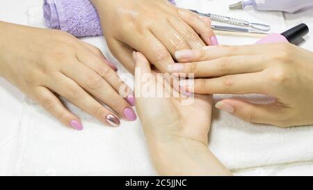 Manicure. Il manicurista applica un idratante alle mani del cliente. Crema per le mani, cura della pelle. SPA, salone di bellezza, procedura. Lozione per le mani, salsa Manicure Foto Stock