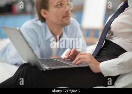 Uomo che si stendeva vicino alla moglie mentre sta lavorando. Primo piano di una donna d'affari che scrive le mani sul computer portatile. Giovani lady mani teneri che lavorano sul computer Foto Stock