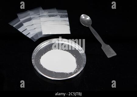 Polvere di cocaina e farmaci in sacchetti di plastica su superficie di vetro nera. Vista dall'alto del concetto di tossicodipendenza Foto Stock