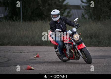 Uomo che corre moto in curva asfaltata con rurale, moto pratica inclinando in una curva veloce in pista Foto Stock