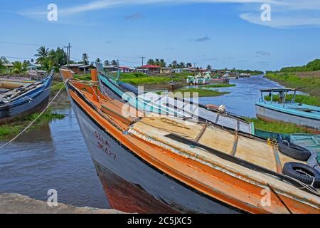 Colorate barche da pesca tradizionali in legno ormeggiate lungo la costa della Guyana, in Sud America Foto Stock