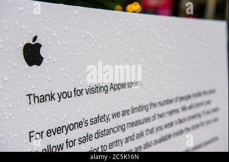 Glasgow, Scozia, Regno Unito. 3 luglio 2020. Nella foto: Il negozio Apple di Buchanan Street, che consiglia ai clienti i nuovi protocolli di coronavirus prima di entrare in negozio, è visto coperto da gocce di pioggia. Area commerciale di Buchanan Street con gli acquirenti che sfidano la pioggia battente utilizzando ombrelloni e rivestimenti facciali che diventeranno obbligatori il 10 luglio della prossima settimana. Credit: Colin Fisher/Alamy Live News Foto Stock