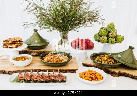 Buffet mediorientale con costolette di maiale, pane pita, hummus, couscous e tagine Foto Stock