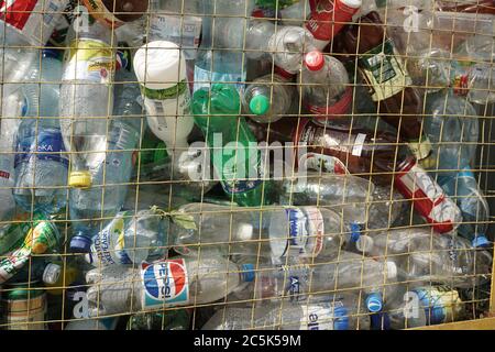 Bottiglie di plastica in una lattina di cestino. Contenitore con bottiglie di Pepsi, Sprite, Schveppes e anche di acqua e latticini. Riciclaggio e smistamento Foto Stock