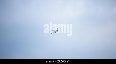 Aereo che vola in alto in cielo blu. Piano bianco con coda rossa. Aprile 2013. Vienna, Austria Foto Stock