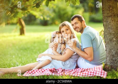 La famiglia felice sta abbracciando mentre si siede nel parco. Foto Stock