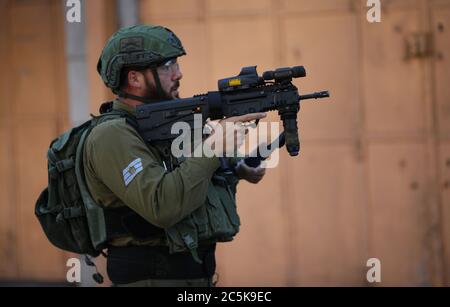 Hebron. 3 luglio 2020. Un soldato israeliano punta la sua arma ai manifestanti palestinesi durante gli scontri dopo una protesta contro il piano di annessione israeliano nella città di Hebron, in Cisgiordania, il 3 luglio 2020. Credit: Yamon/Yamon Live News Foto Stock