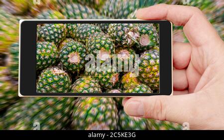Ananas sullo schermo dello smartphone. Vendita di ananas in supermercato. Frutti tropicali. Foto Stock