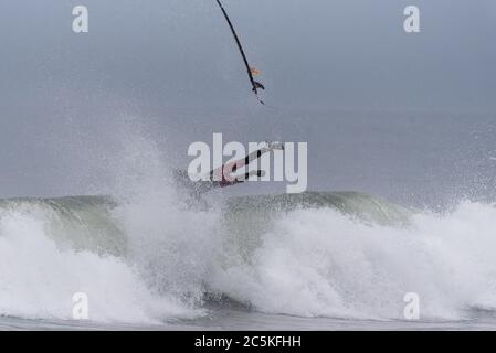 Solo le gambe e i piedi di Surfer con muta si mostrano dopo il wipeout sull'onda mentre la tavola da surf spara in aria. Foto Stock