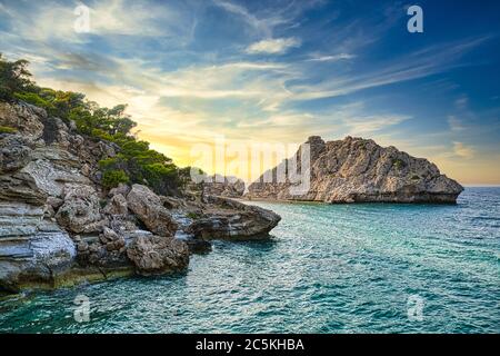 Splendido tramonto sulla spiaggia selvaggia, Mar Mediterraneo, Grecia. Foto Stock