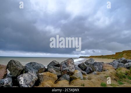 3 la barriera rocciosa che protegge le scogliere sabbiose in una giornata intensa sulla spiaggia di Happisburgh, costa nord del Norfolk Foto Stock