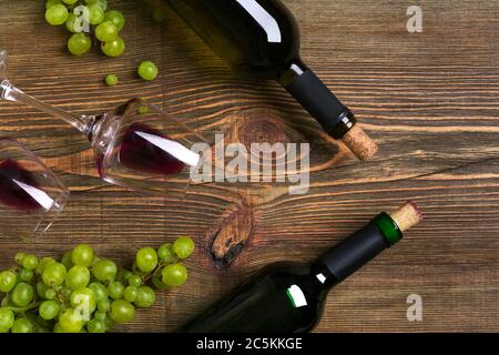 Bottiglie di vino rosso e bianco, uva e bicchieri su tavola di legno. Vista dall'alto con spazio per la copia Foto Stock