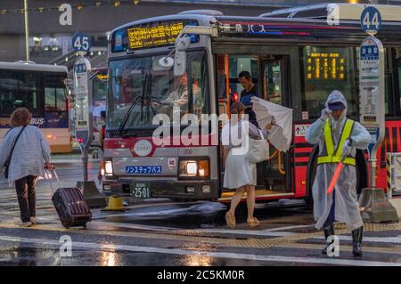 Persone che salite a bordo di un autobus alla Stazione di Shibuya, in una notte di pioggia, Tokyo, Giappone Foto Stock