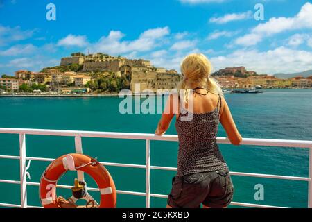 Donna caucasica che guarda Portoferraio porto cittadino su traghetto per l'Isola d'Elba. La donna turistica italiana viaggia all'Elba. Vacanze in Italia, Europa Foto Stock