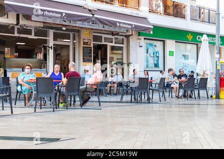 Punta Umbria, Huelva, Spagna - 3 giugno 2020: Persone sedute in terrazza di un bar e caffetteria in via calle Ancha di Punta Umbria, Huelva, Spagna Foto Stock