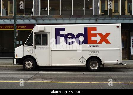 Un corriere FedEx Express per la consegna dei pacchi si trova parcheggiato in una strada del centro di Vancouver, British Columbia, Canada, fuori da un centro bancario CIBC. Foto Stock