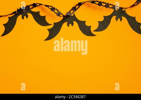 Halloween pipistrelli e nastro nero su sfondo arancione. Mockup banner Halloween. Disposizione piatta, vista dall'alto. Foto Stock