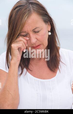 Ritratto attraente donna matura che guarda triste e depresso, piangendo, occhi chiusi. Foto Stock
